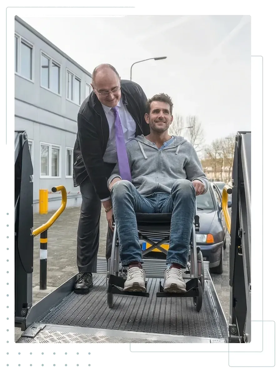 Fahrer bringt einen Rollstuhlfahrer über die Hebebühne in den Transporter
